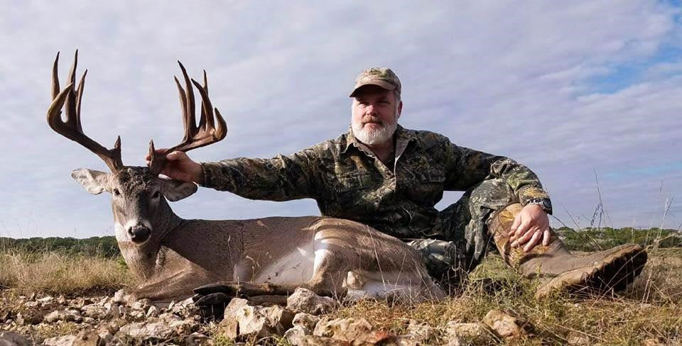 the hunter sits with his deer just caught