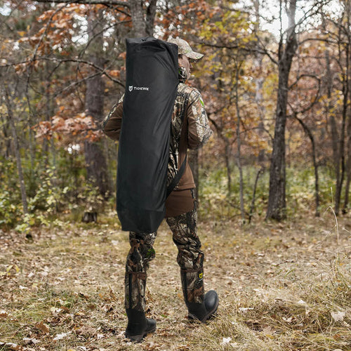 A man in camouflage carrying a black bag in the woods, showcasing the 270 Degree 3 Full Panels See Through Hunting Blind 2 Sets Bundle.