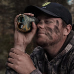 Man wearing a hat and using binoculars, showcasing the 270 Degree 3 Full Panels See Through Hunting Blind and Rangefinder Bundle for optimal outdoor hunting experiences.