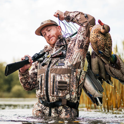 A duck hunter with waders on, in the river