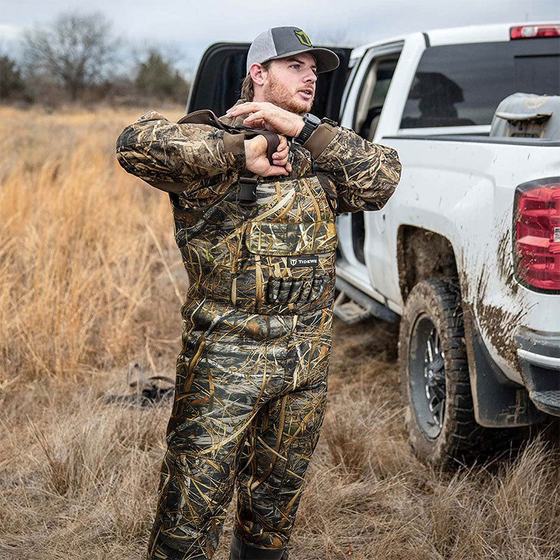 Man in camouflage outfit standing by truck, showcasing TideWe Hunting Wader Waterfowl Waders (600G & 800G) for Men Women, highlighting its sturdy and waterproof design.